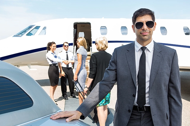 A picture of one of our chauffeurs in an FBO private airport near a jet meeting our customers